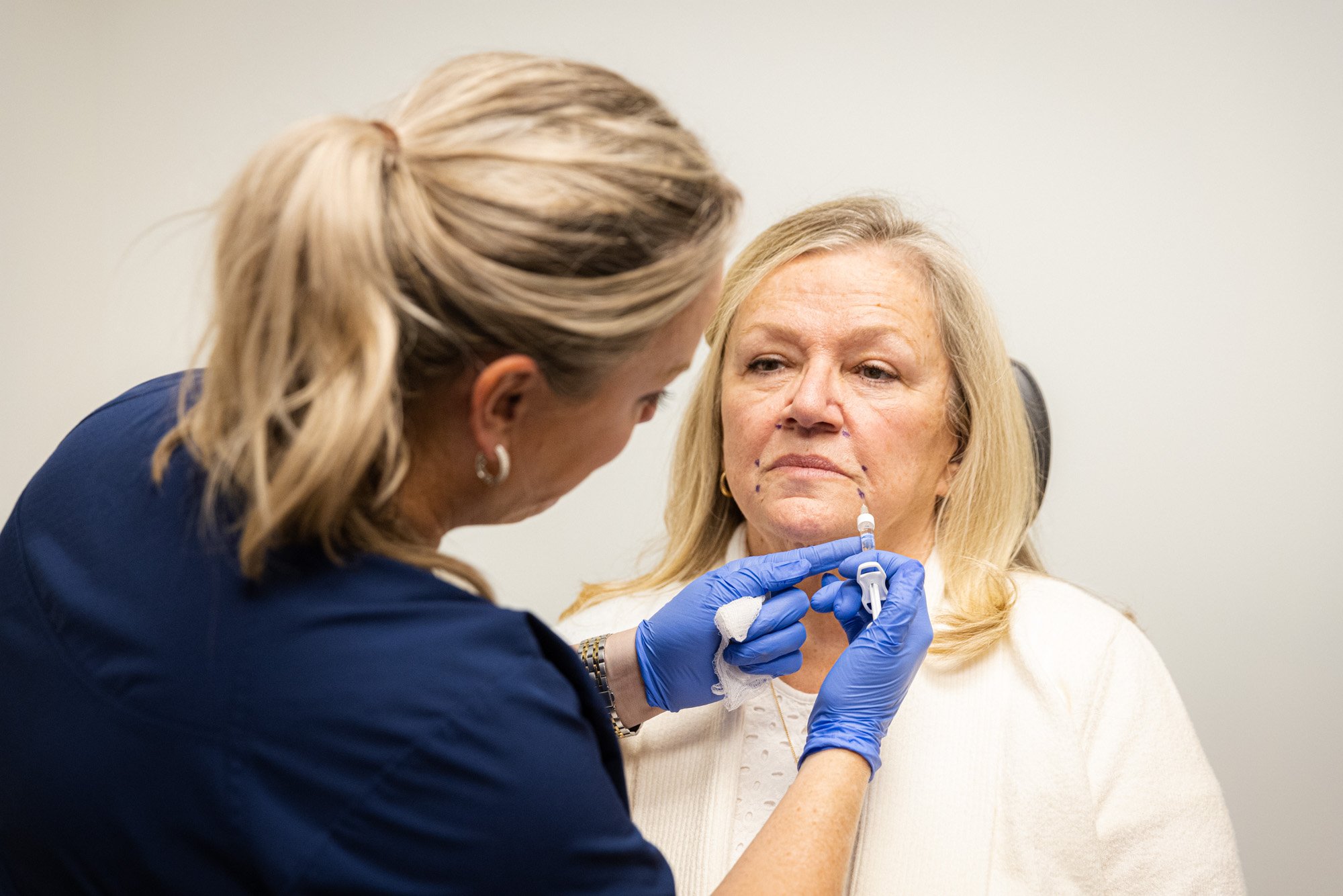 A specialist injects dermal fillers into pre-planned areas of a patient's face.