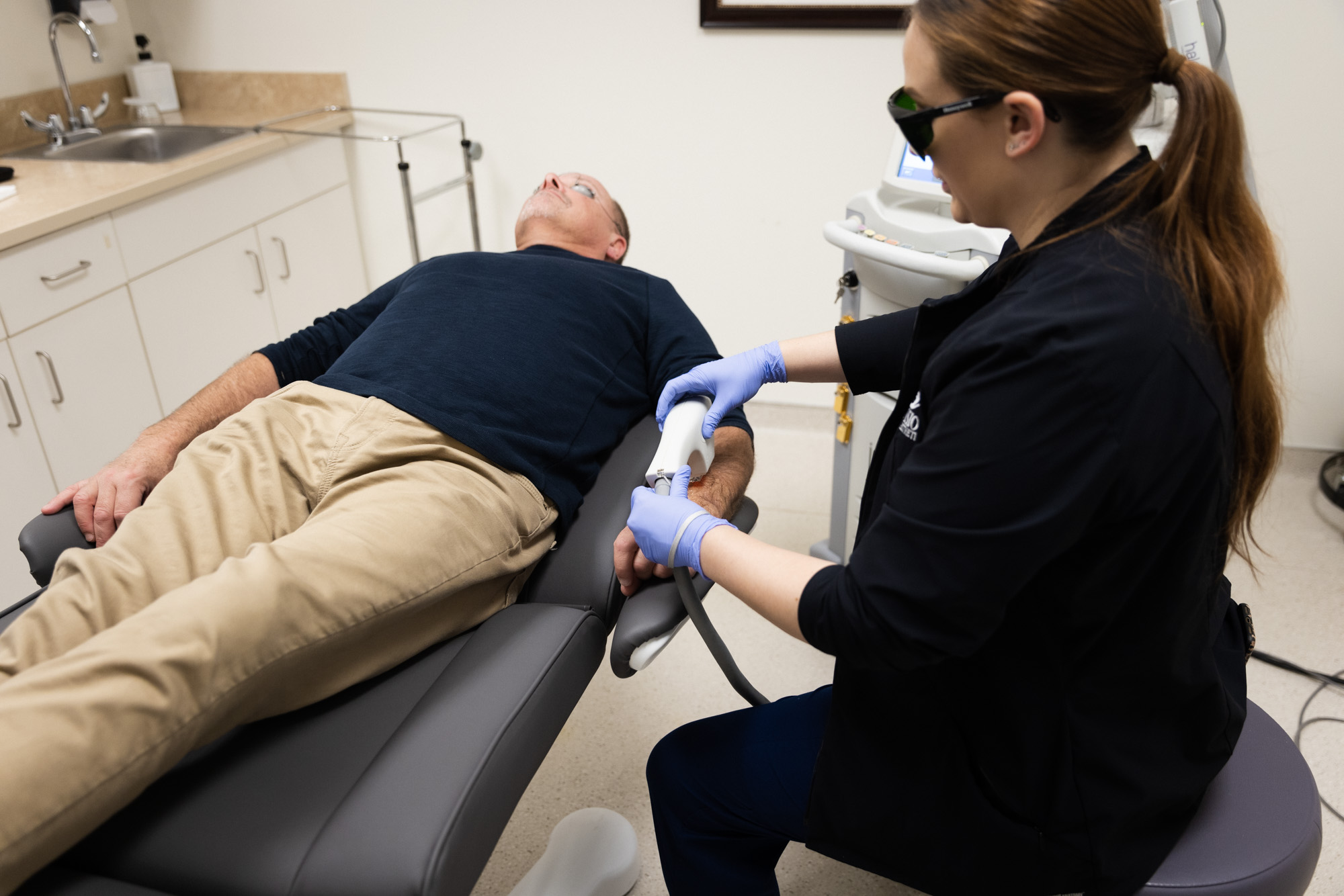An Envision specialist ensures a patient's comfort during his laser hair removal.
