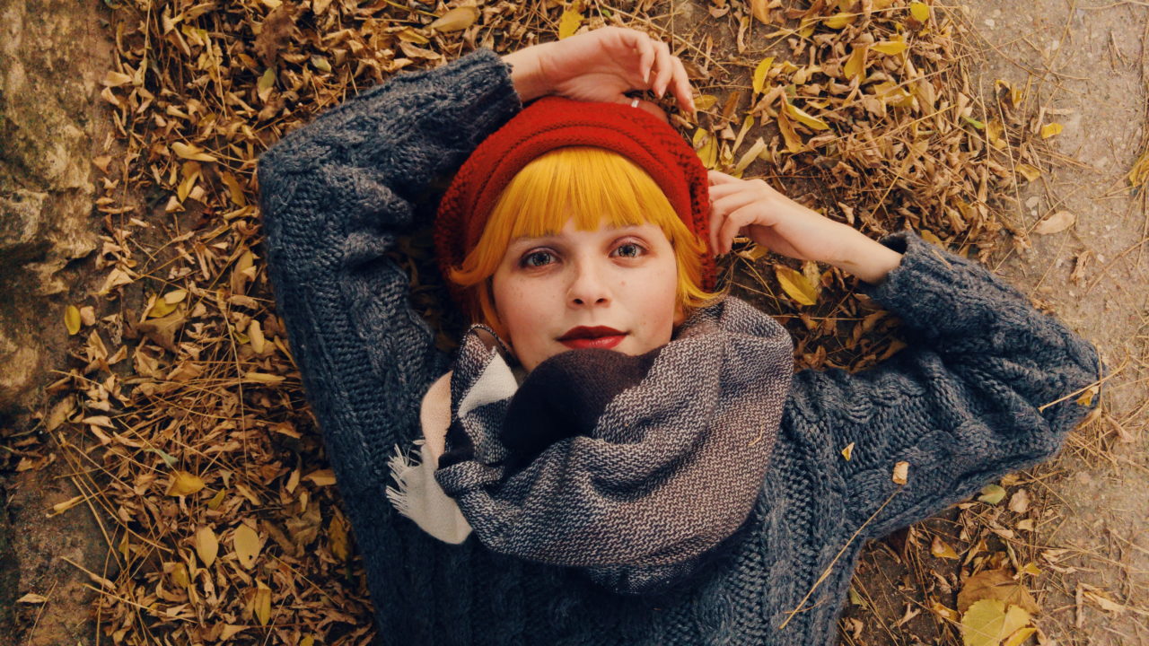 woman in rochester new york laying in a pile of leaves feeling refreshed after a medical spa appointment
