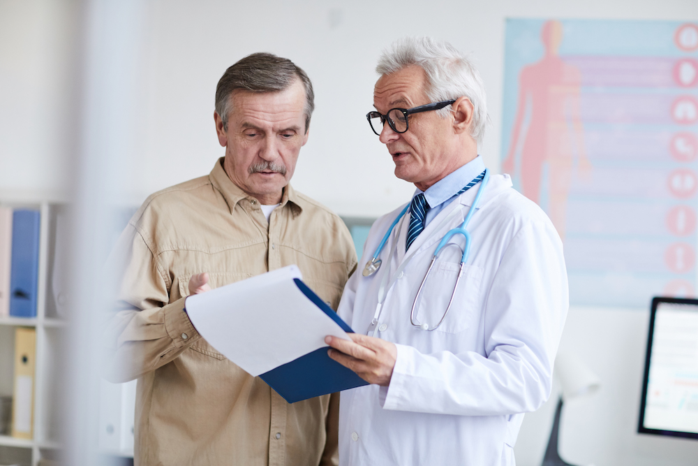 mature male patient looking at notes with a hair surgeon in upstate New York